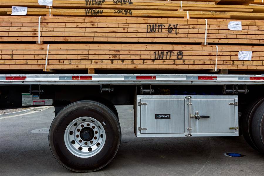 Banded lumber units strapped down on a flatbed trailer deck